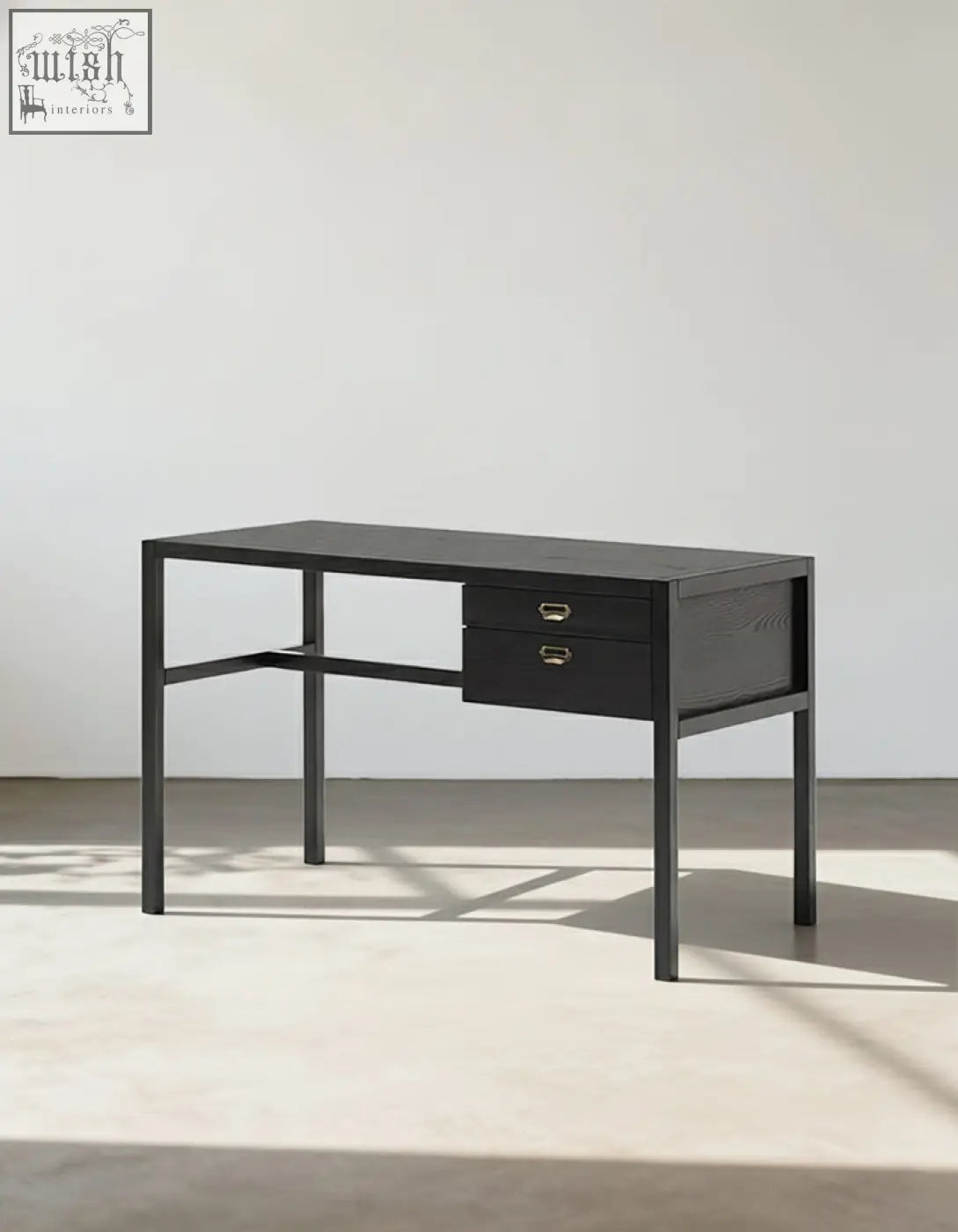 Black minimalist jottergoods office desk with two drawers, brass handles, and slender metal legs for workspace