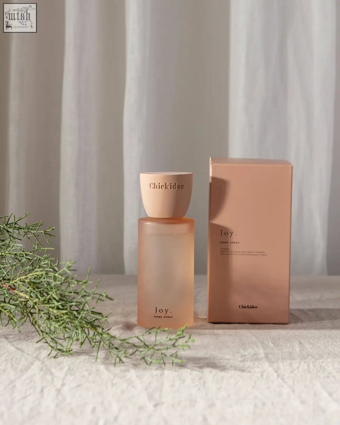 A matte peach-colored glass bottle with ceramic cap labeled joy for joy clay home clay home spray product