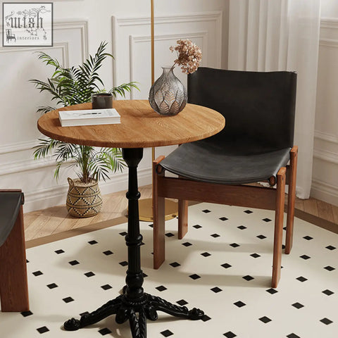 Round solid wood table with black ornate metal base paired with judith dining chair in black for stylish dining