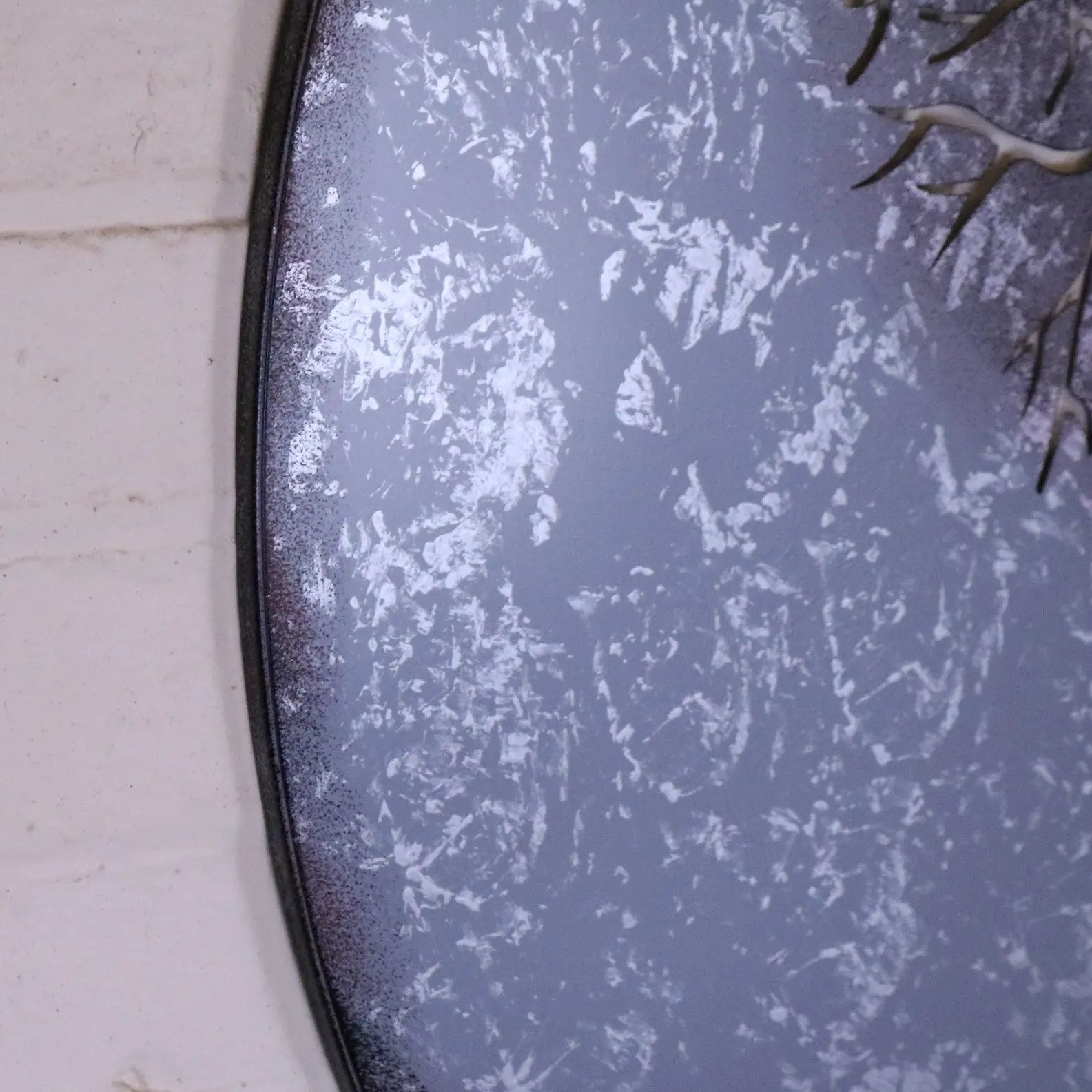 A round distressed gray mirror with a dark metal frame perfect as kailora tree metal garden wall art or garden wall decor