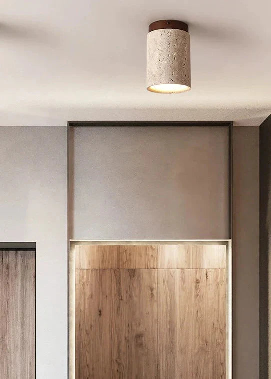 A cylindrical concrete kaku light with speckled texture and warm diffused glow for cozy ceiling lighting
