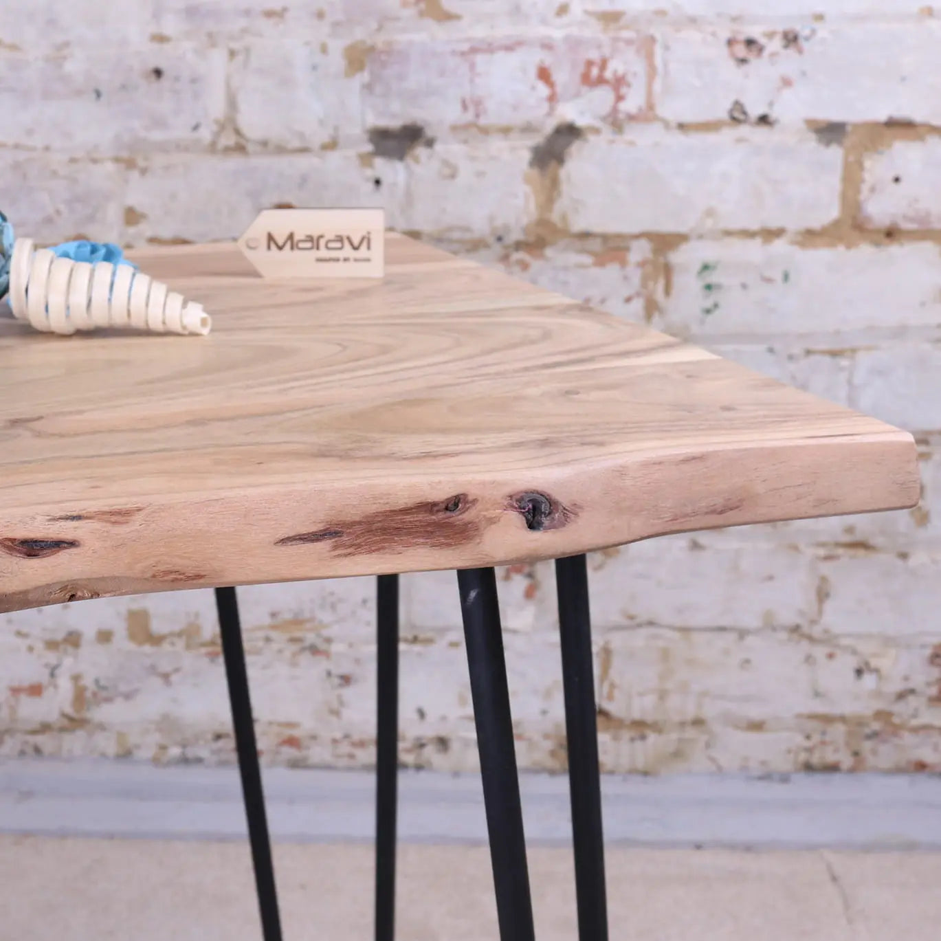 Light-colored kalan live edge wooden table with natural edge and black metal hairpin legs for stylish spaces