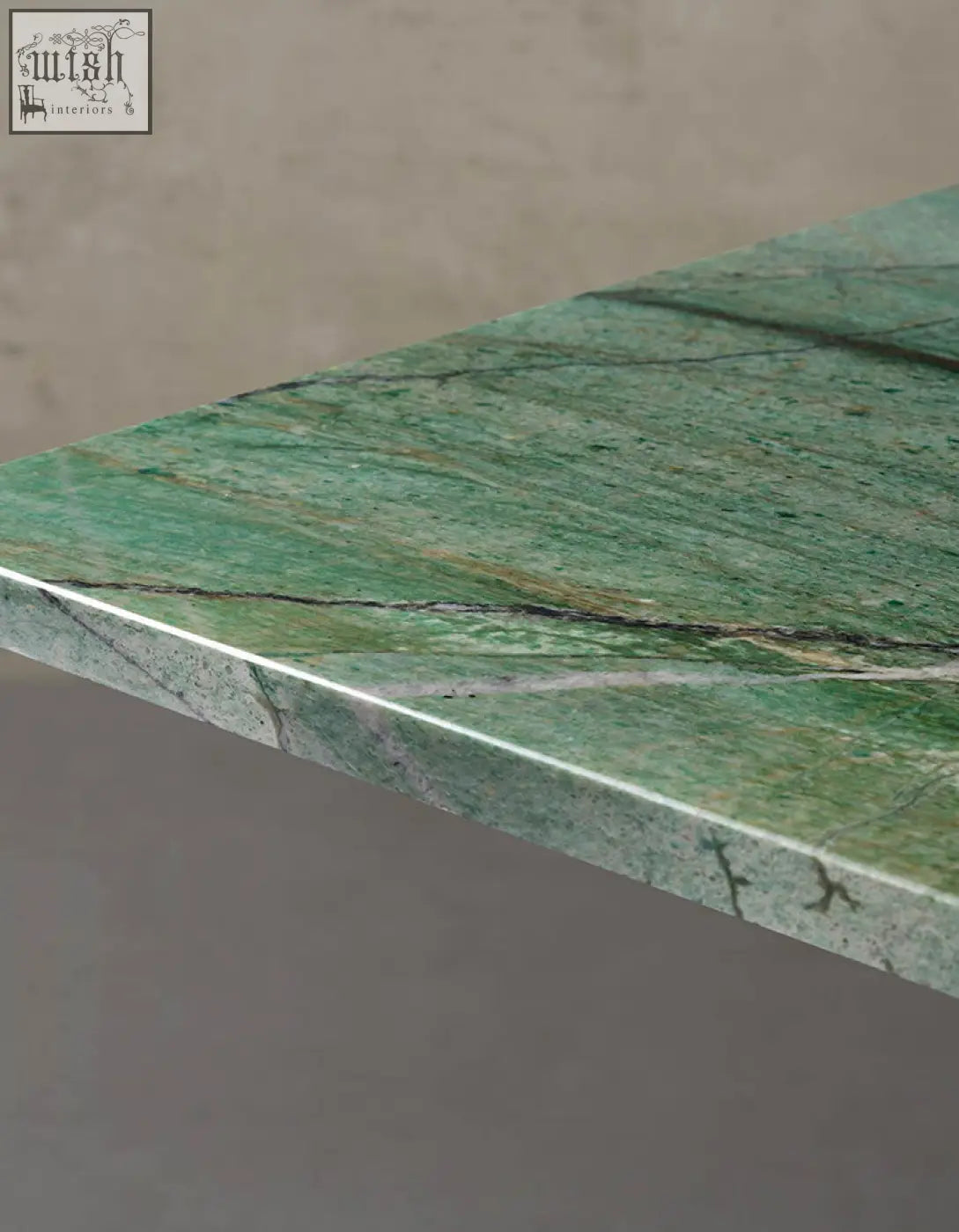 Kamara dining table with green marble dining tabletop featuring natural veining and a sleek polished edge