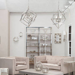 A pair of metallic kamara square design chandeliers with intricate wireframe shapes hanging from the ceiling