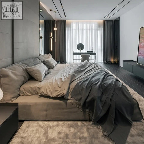 A kamoto bed with plush dark gray upholstery and a soft fringe draped over its sturdy frame