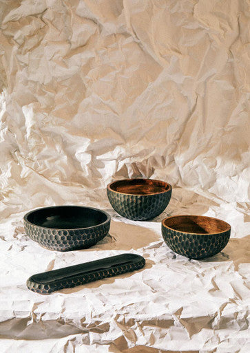Three kara black mango wood bowls with honeycomb texture and natural wood interiors next to a matching serving tray