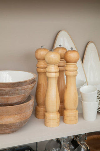 Set of four light wood pepper mills with rounded tops and stacked bases on kara large mango wood serving platter