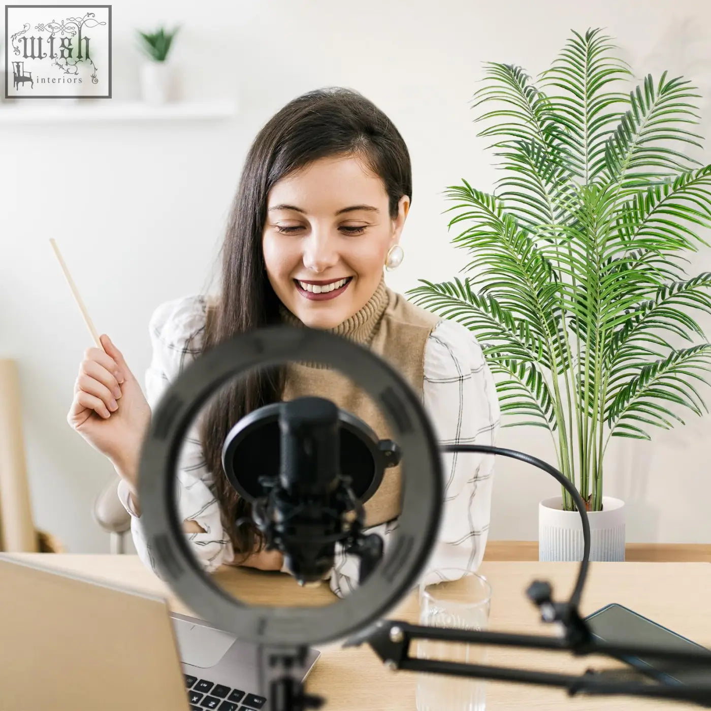 Black ring light with built-in microphone and shock mount beside tall keeplush artificial palm tree with real bark design