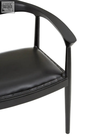 Black leather kendari black chair with sleek curved teak wood frame and subtle nailhead trim on seat edge