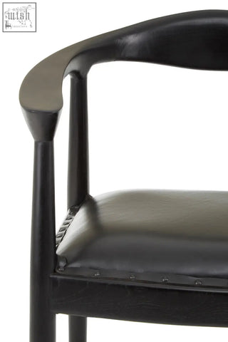 Kendari black leather chair with sleek curved teak wood frame and subtle metallic rivets along seat edge