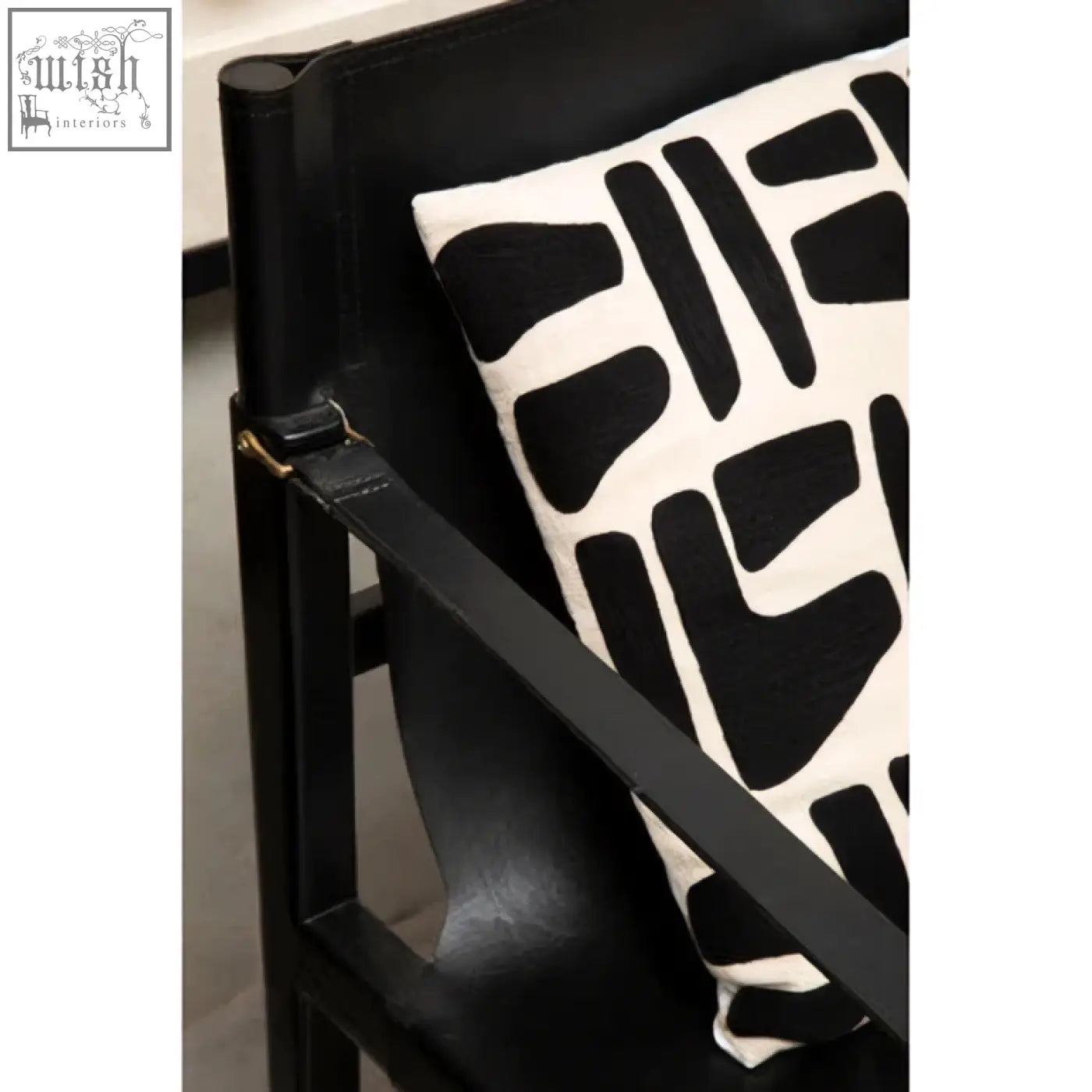 Black and white abstract patterned throw pillow on a kendari teak wood frame armchair with wood frame design