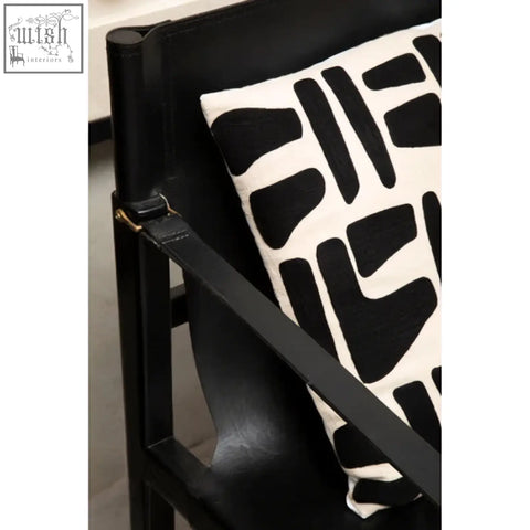 Black and white abstract patterned throw pillow on a kendari teak wood frame armchair with wood frame design