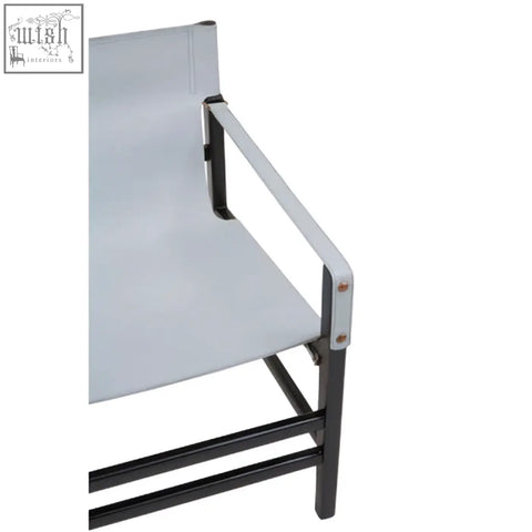 Silver metal armrest attached to black frame on white fabric surface of kendari grey leather and black teak wood chair
