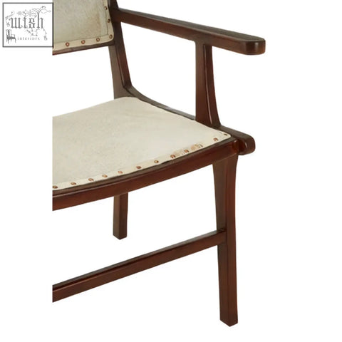 Dark wood teak wood dining chair with cream fabric seat and back accented by brass studs for stylish wood dining