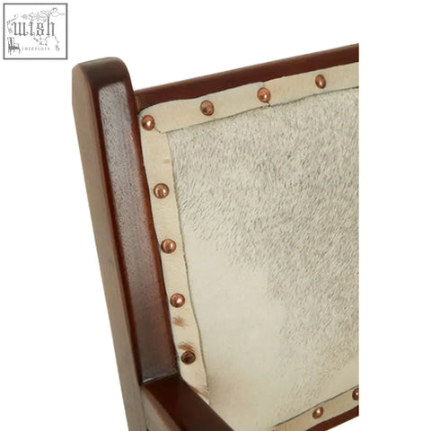 The kendari leather and teak wood dining chair features a dark teak wood frame with off-white textured upholstery and copper nailhead trim