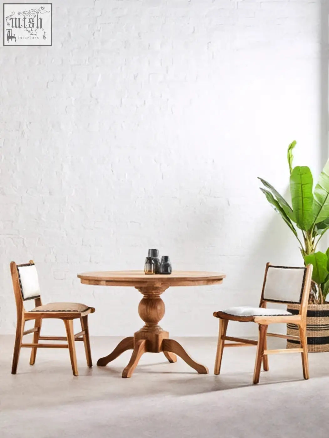 Round wooden table with a central pedestal base and four splayed legs paired with kendari natural leather teak wood dining chair