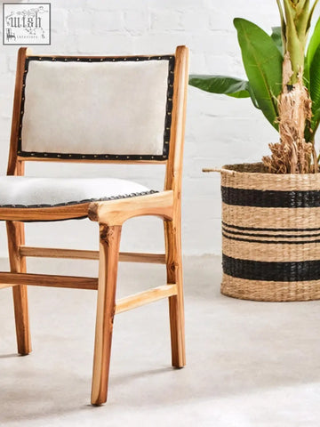 A kendari natural leather teak wood dining chair with a rustic wooden frame and light beige upholstered seat and back