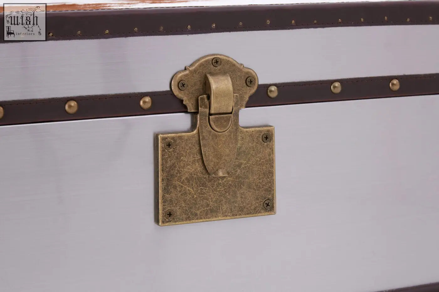 Antique brass lock with ornate design on white trunk of kensington townhouse brown and white cowhide cabinet