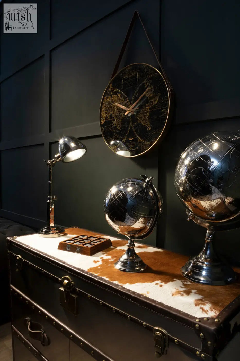 Shiny chrome globe with detailed world map on a classic pedestal beside the kensington townhouse brown and white cowhide cabinet
