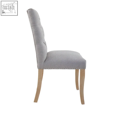 Grey linen dining chair with tufted upholstery and light wood legs perfect for kensington townhouse style dining rooms