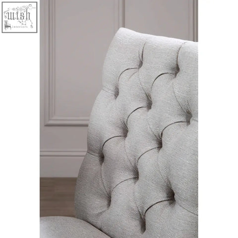 A light gray tufted linen dining chair with a classic button-tufted backrest perfect for dining rooms