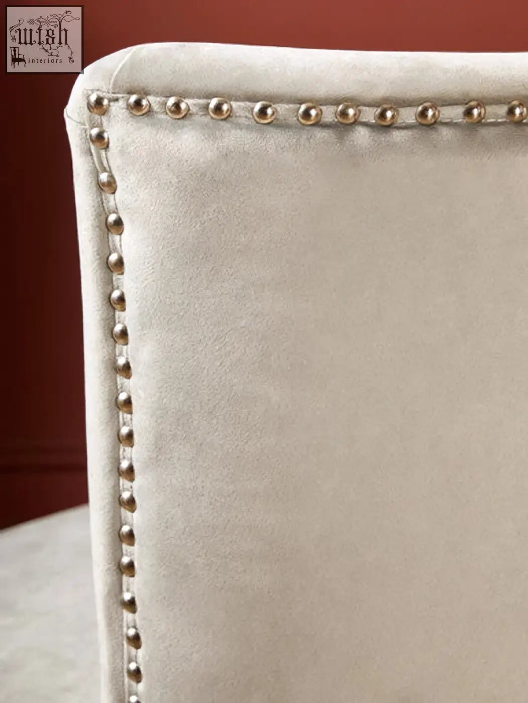 Beige upholstered back of kensington townhouse grey winged dining chair with silver nailhead trim detail