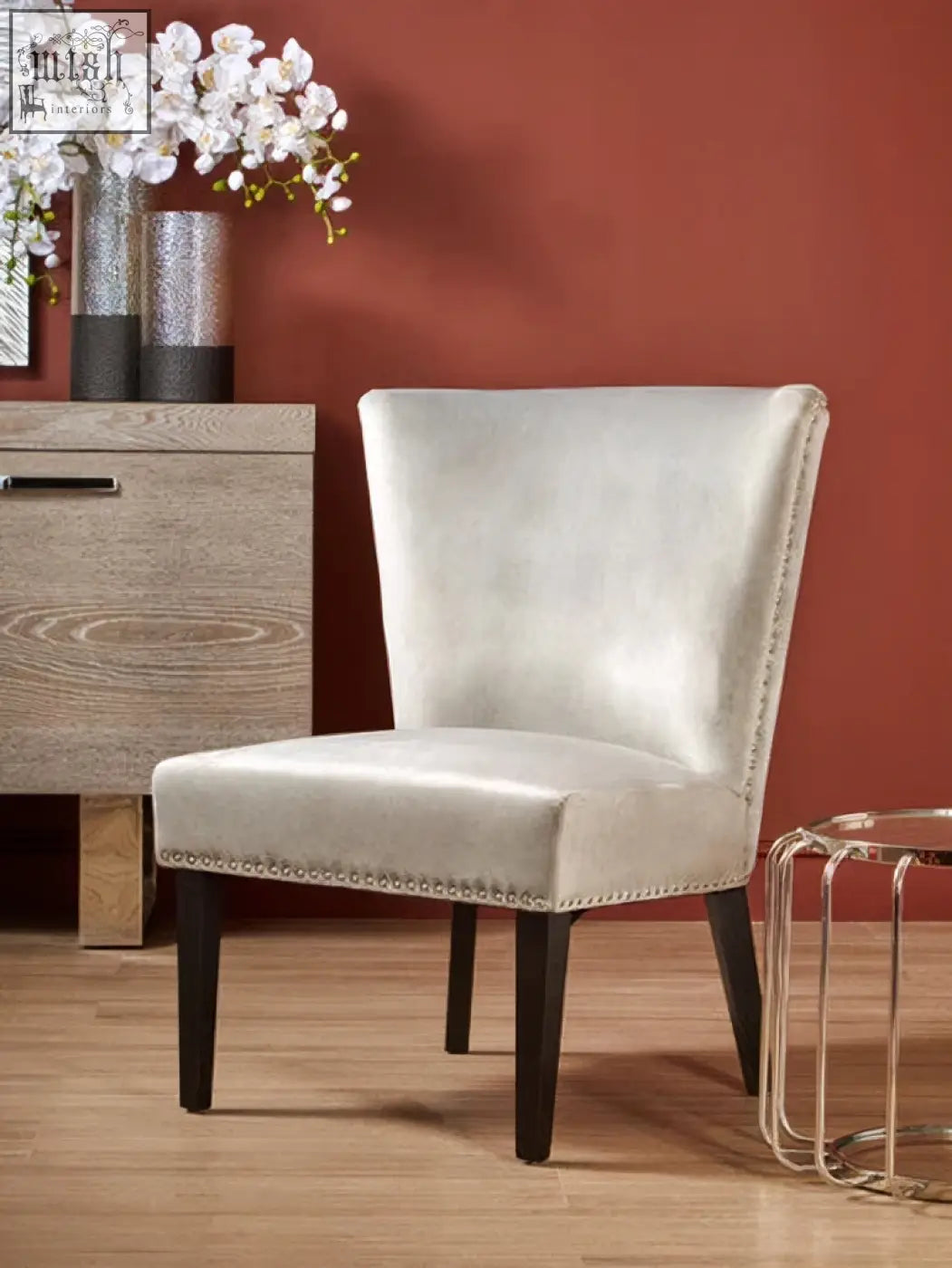 A sleek off-white upholstered kensington townhouse grey winged dining chair with dark wooden legs and nailhead trim