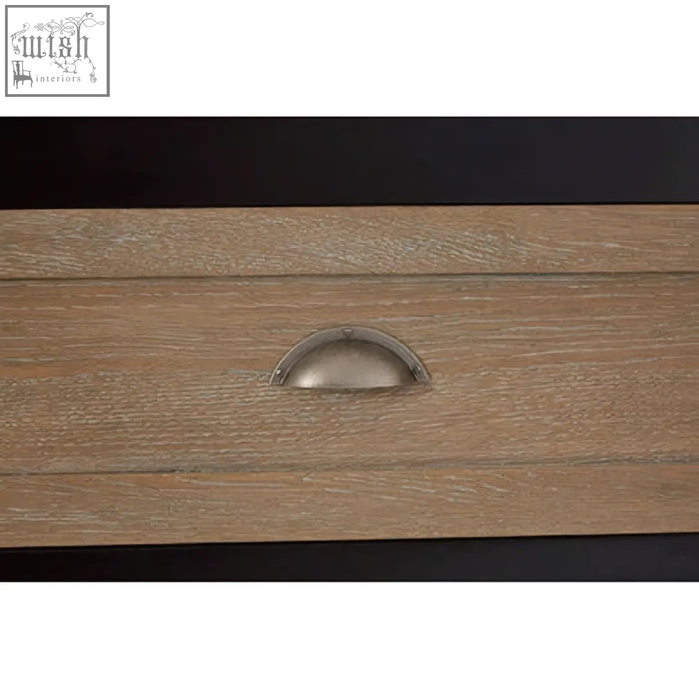 A sleek silver half-moon drawer pull on light oak wood of the kensington townhouse sideboard