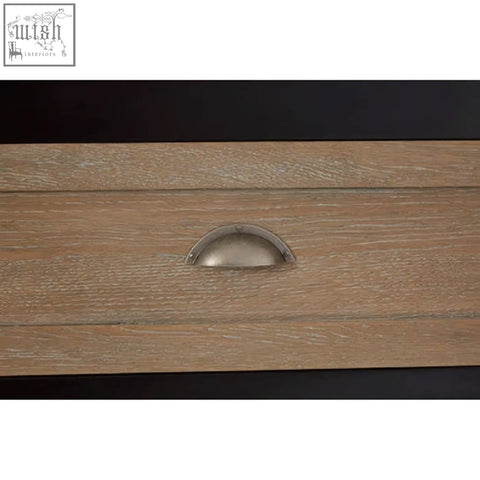 A sleek silver half-moon drawer pull on light oak wood of the kensington townhouse sideboard