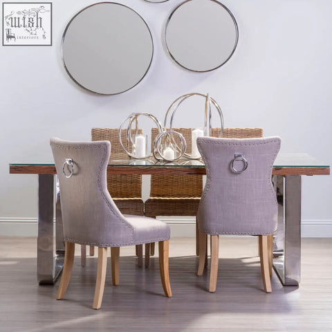 Light gray upholstered dining chairs with wooden legs and silver ring pulls by kerala natural u shaped base dining table