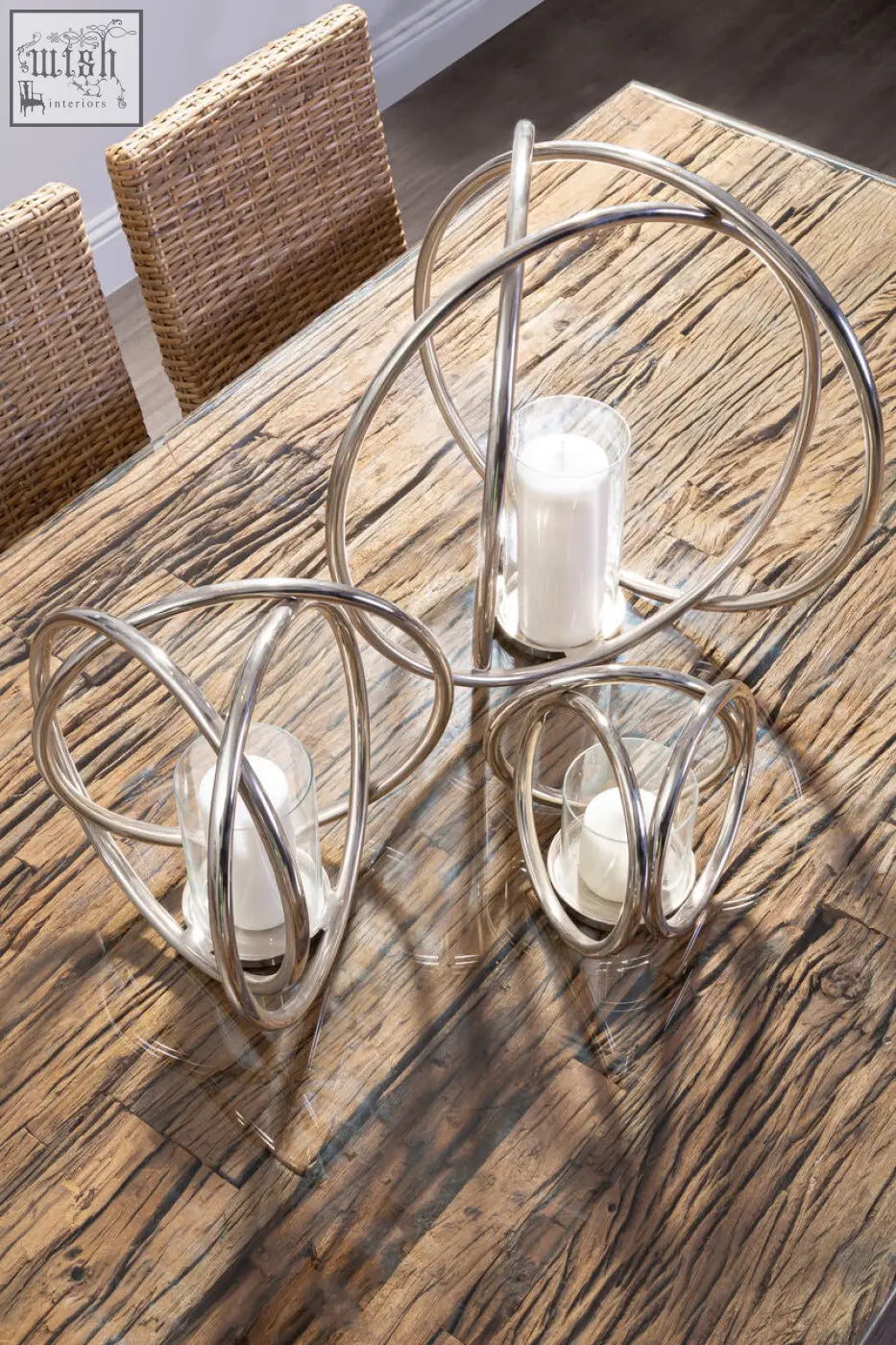 Set of three modern metallic candle holders with white pillar candles complementing a base dining table style