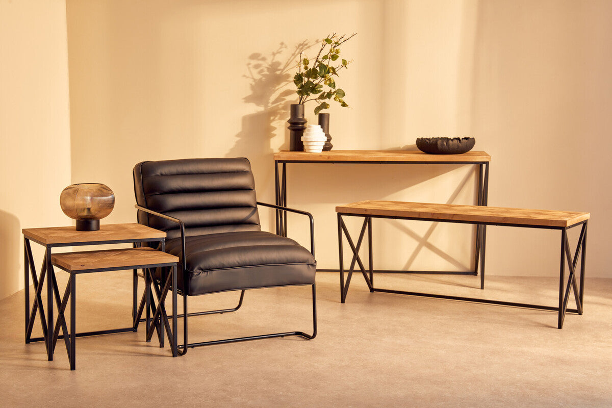 Black leather armchair with ribbed back and sleek metal frame next to kickford parquet fir wood set of two nesting tables
