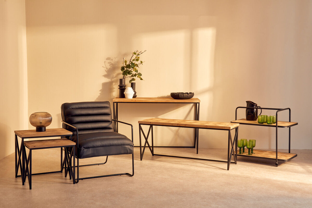 Black leather armchair with ribbed back and sleek metal frame paired with kickford parquet fir wood set nesting tables