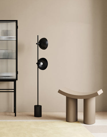 Black floor lamp with two circular shades and slender pole next to kimber footstool dressing table stool