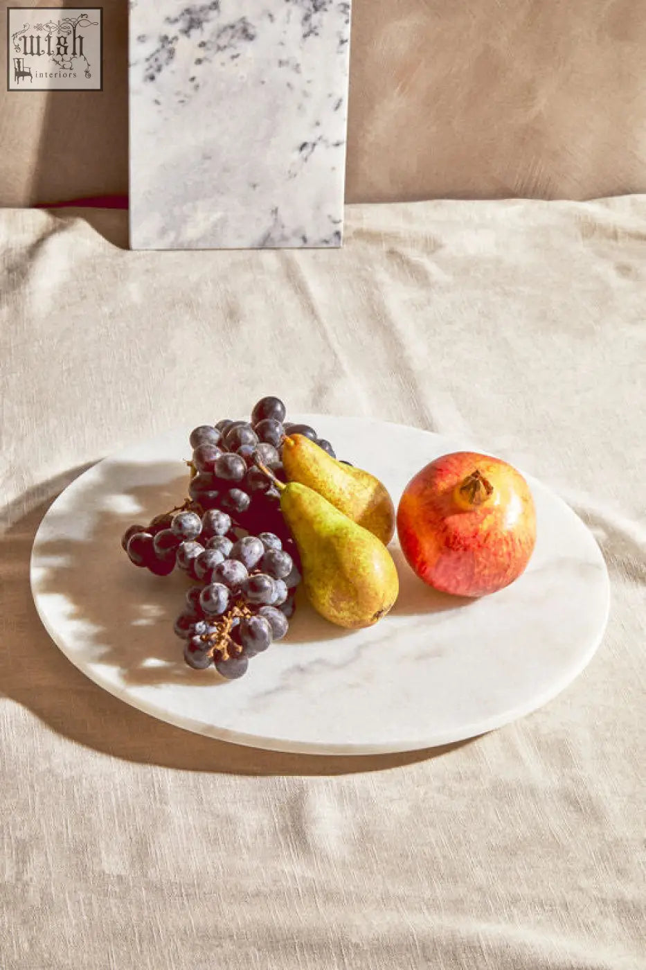 Kindia round white marble lazy susan with subtle gray veining holding grapes pears and a pomegranate