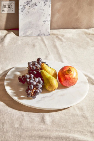 Kindia round white marble lazy susan with subtle gray veining holding grapes pears and a pomegranate