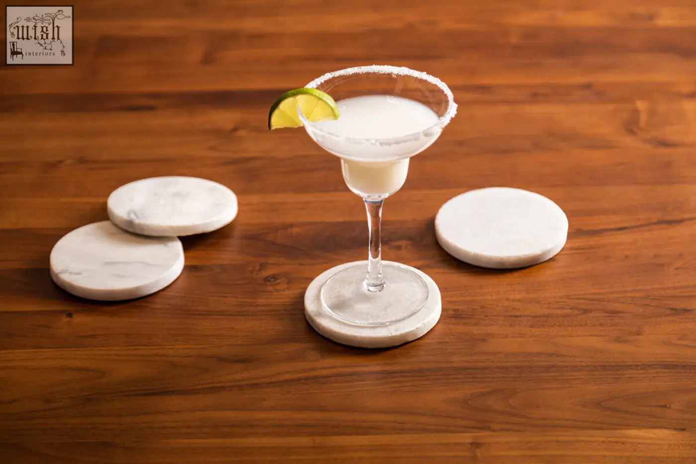 A white marble round coaster with gray veining from the kindia set of 4 marble round coasters under a margarita glass