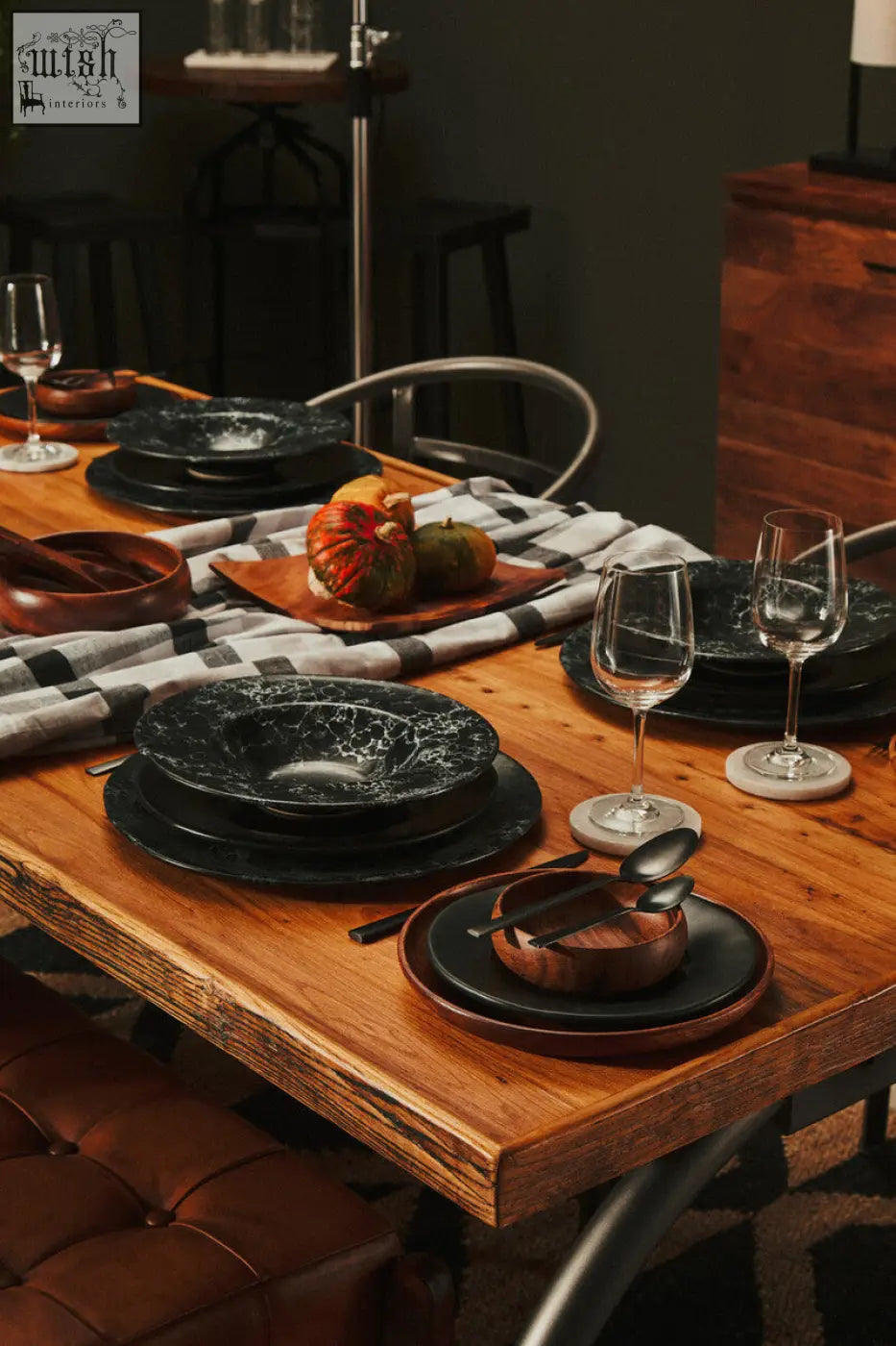 Black ceramic dinnerware set with marbled texture paired with white marble round coasters on rustic wooden table