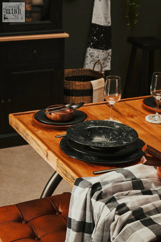 Black marble-patterned dinnerware set with glossy finish arranged on rustic table featuring white marble round coasters