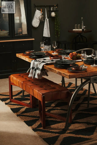 Brown tufted leather dining bench with wooden legs shown next to white marble round coasters for stylish dining decor