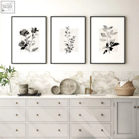 Three black-framed monochrome botanical prints hanging above a marble countertop perfect for kitchen art wall decor