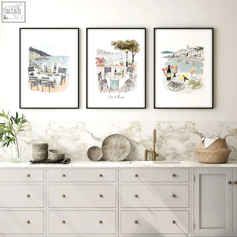 Three framed sole di amalfi kitchen paintings with mediterranean coastal watercolor scenes hang above marble countertop