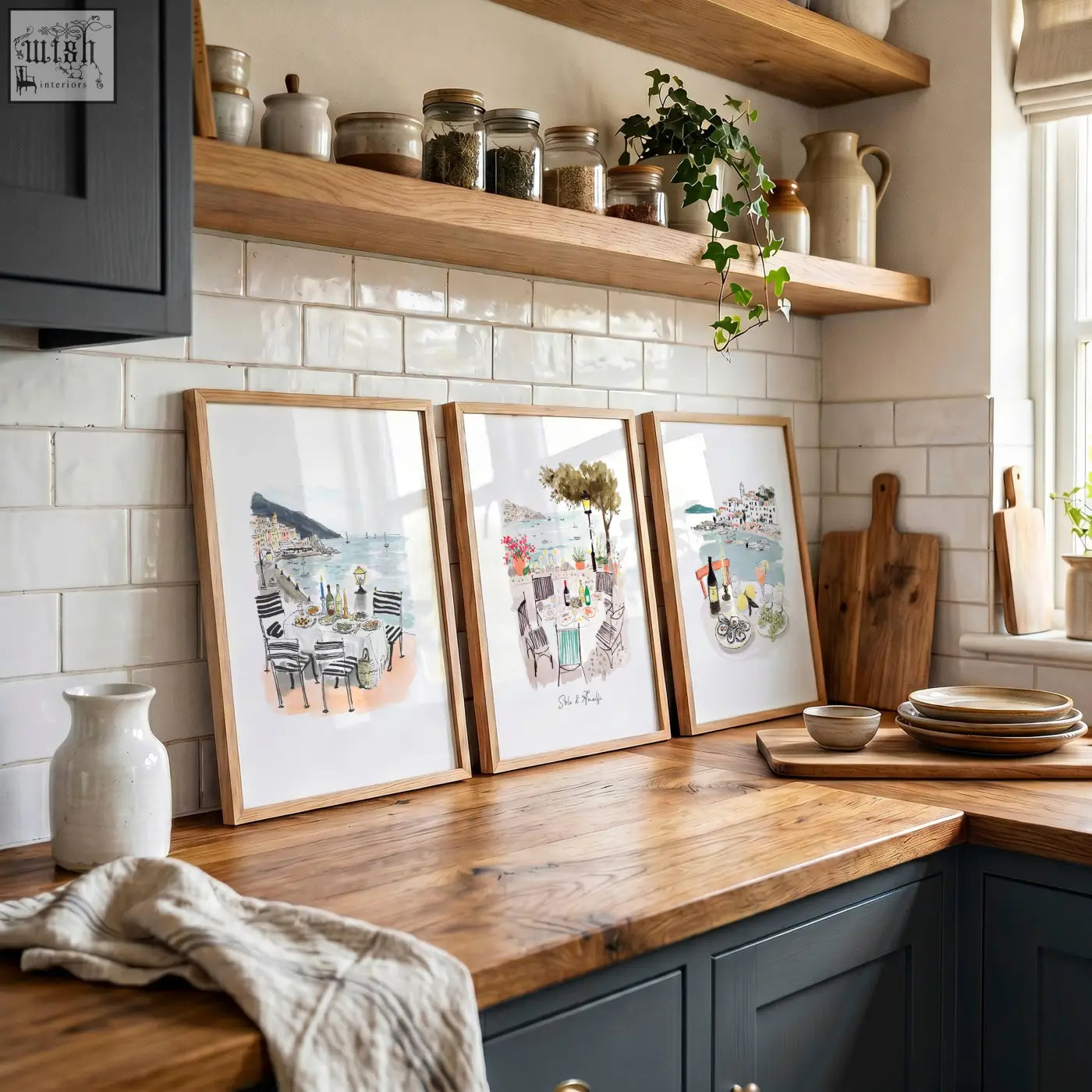 Three kitchen paintings in light wood frames featuring sole di amalfi mediterranean coastal scenes with tables and chairs