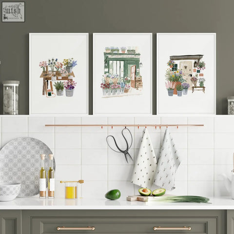 Three framed watercolor flower shop kitchen prints hang above a counter in a country cottage style kitchen