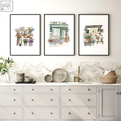 Three black framed botanical kitchen prints hanging above a marble countertop for country cottage flower shop decor