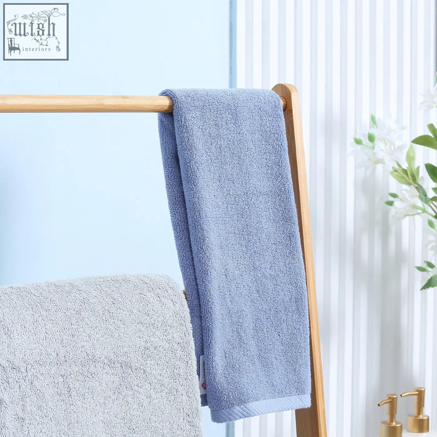 A soft light blue towel hangs on a kleankin freestanding natural bamboo towel rack with three rails and shelves