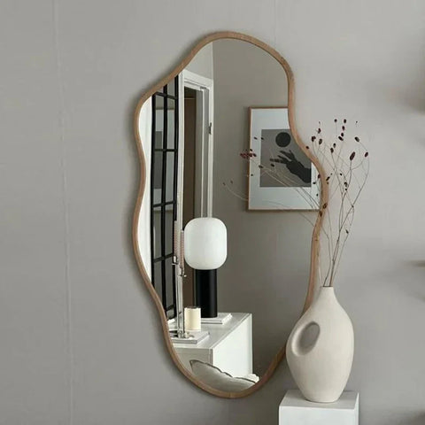A kohana mirror with a light wood frame and smooth natural finish in an irregular shape
