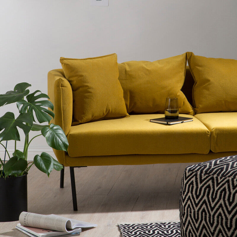 Kolding two seater yellow sofa made of mustard velvet with black metal legs and matching throw pillows