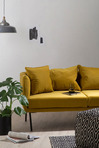 A vibrant mustard-yellow velvet kolding two seater sofa with sleek black metal legs and matching cushions