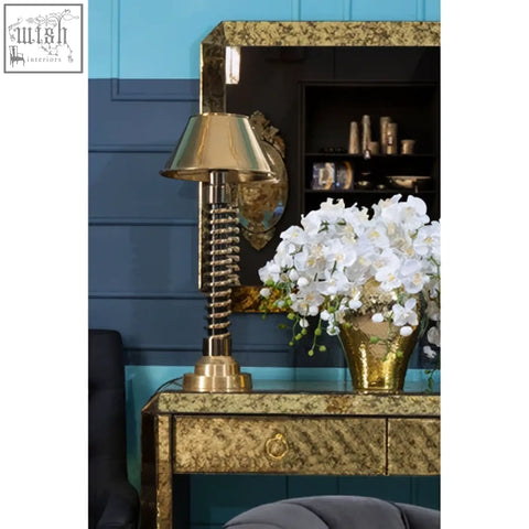 Gold-toned table lamp with conical shade and spiral base on komo console table for stylish lighting accents